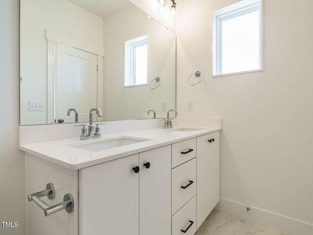 bathroom with marble finish floor, a sink, baseboards, and double vanity