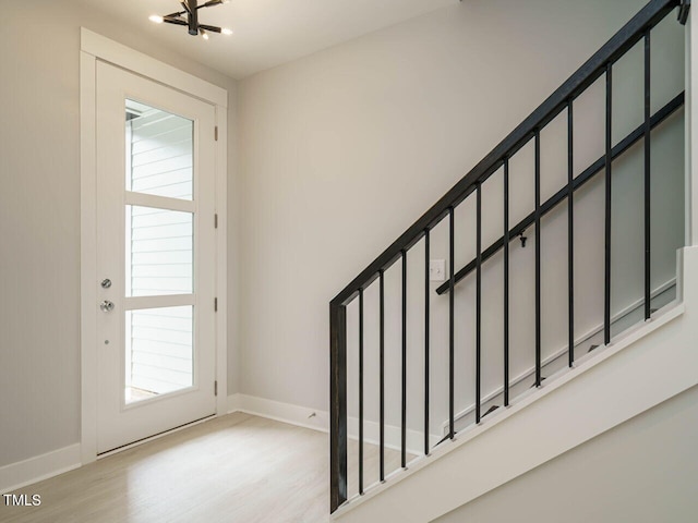 interior space featuring stairs, baseboards, an inviting chandelier, and light wood-style floors