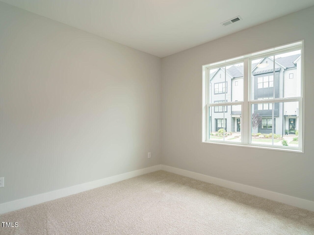 unfurnished room with carpet, visible vents, and baseboards