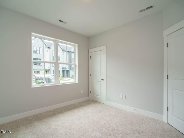 unfurnished room featuring baseboards, visible vents, and carpet flooring