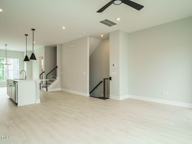 unfurnished room featuring visible vents, a sink, light wood-style flooring, and baseboards