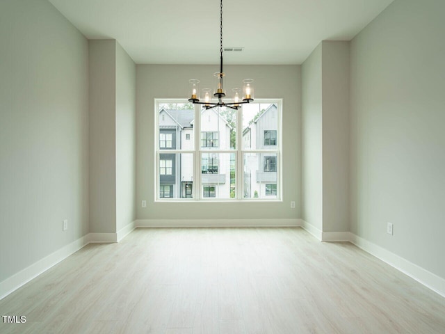 unfurnished dining area with baseboards, light wood finished floors, visible vents, and a notable chandelier