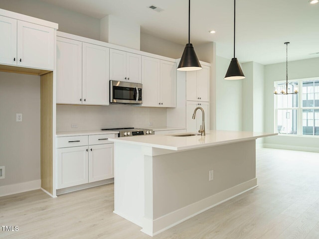 kitchen featuring visible vents, backsplash, appliances with stainless steel finishes, light wood-style floors, and a sink