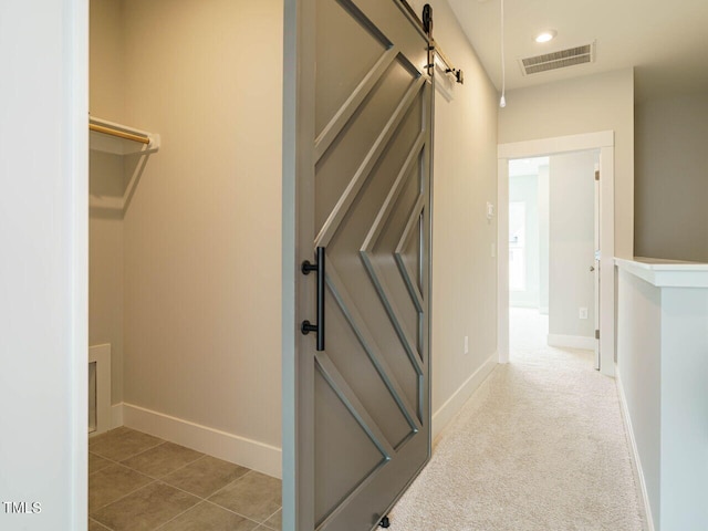 interior space featuring a barn door, carpet flooring, visible vents, and baseboards