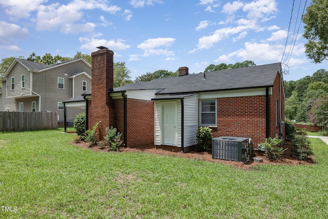 back of property featuring a lawn and central air condition unit