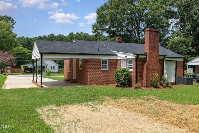 rear view of property featuring a yard, a carport, and central AC