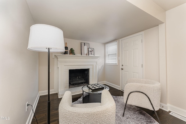 living room with a brick fireplace and dark hardwood / wood-style flooring