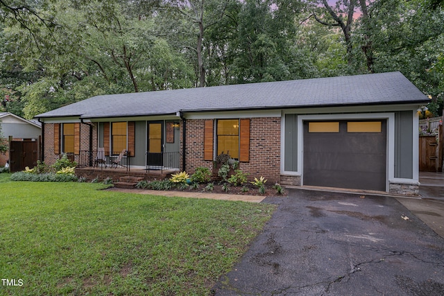 ranch-style home featuring a garage, a porch, and a front yard