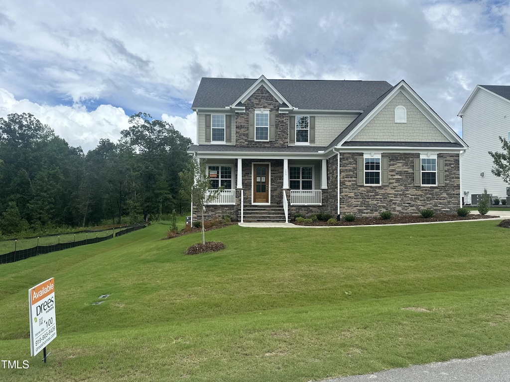 craftsman-style home featuring stone siding, covered porch, and a front yard