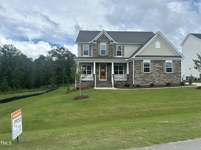 craftsman-style home featuring stone siding, covered porch, and a front yard