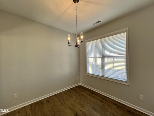 empty room with an inviting chandelier and dark hardwood / wood-style flooring