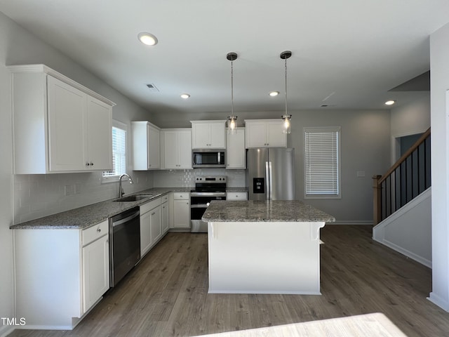 kitchen featuring sink, white cabinetry, a center island, appliances with stainless steel finishes, and hardwood / wood-style flooring