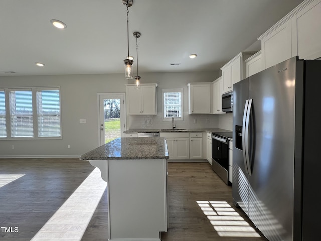 kitchen with sink, white cabinetry, decorative light fixtures, appliances with stainless steel finishes, and a kitchen island