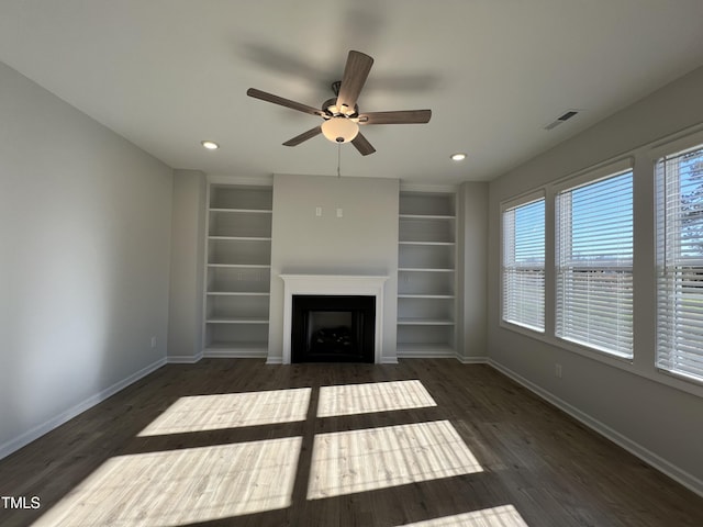 unfurnished living room with dark wood-type flooring, built in features, and ceiling fan