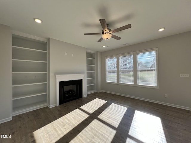 unfurnished living room with dark hardwood / wood-style flooring, built in shelves, and ceiling fan