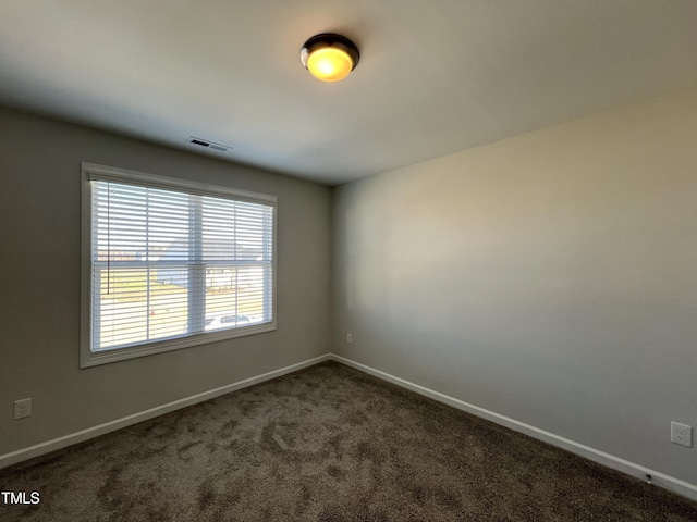 spare room featuring dark carpet