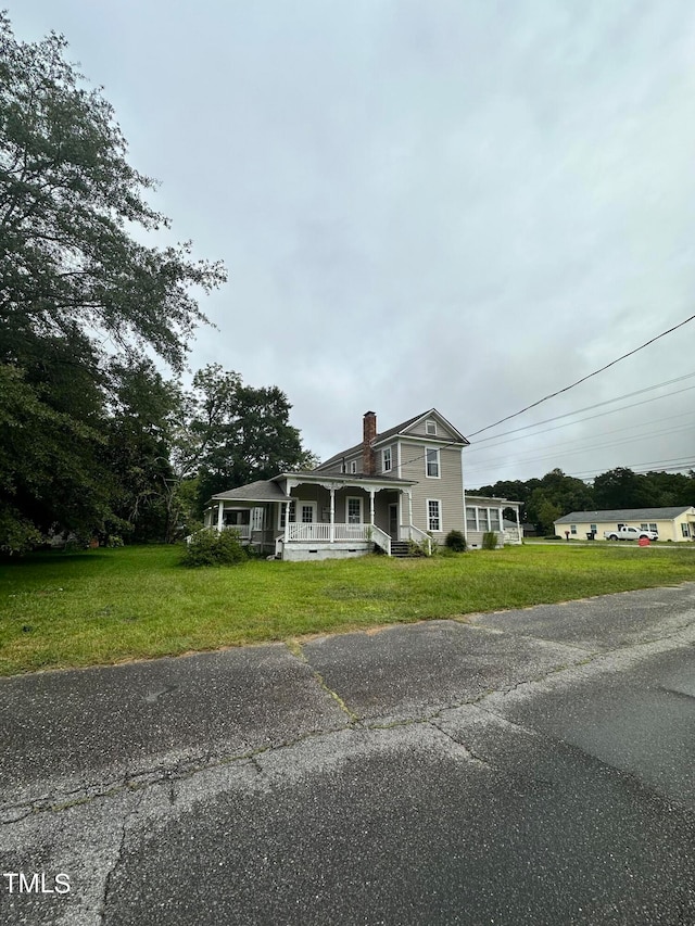 view of front of home with covered porch and a front lawn