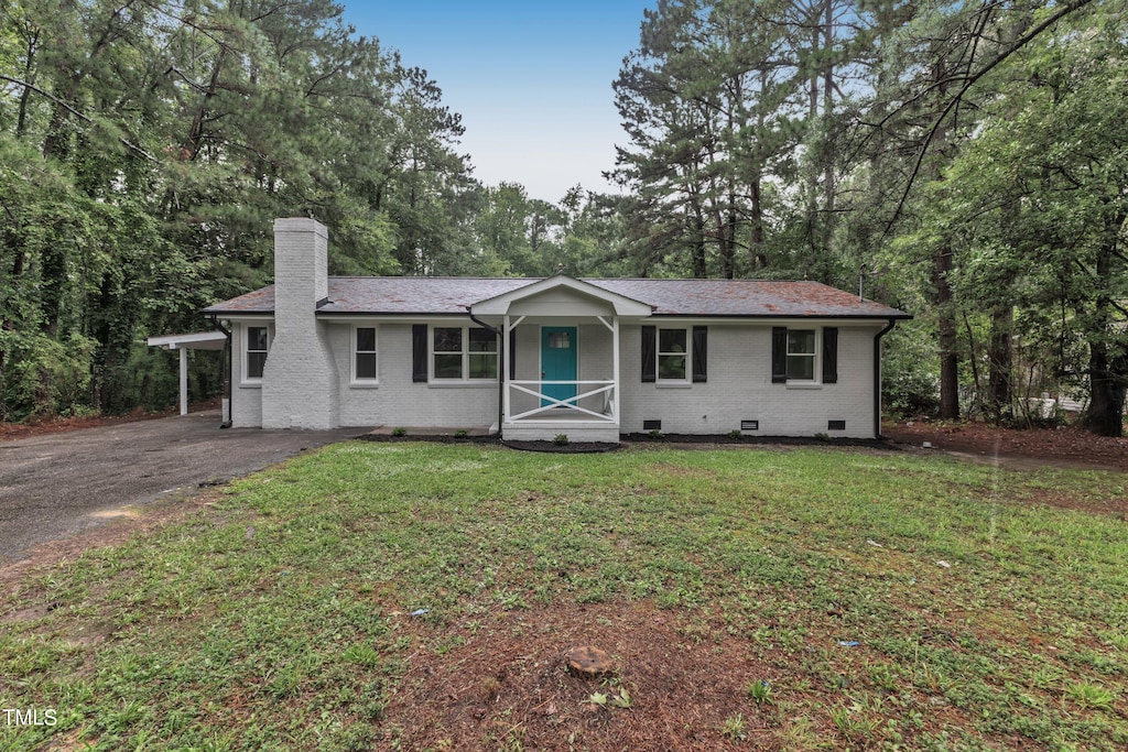 single story home featuring a carport, a front yard, and covered porch