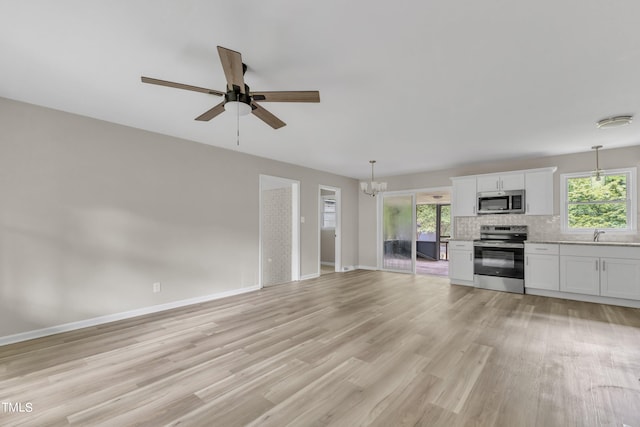 unfurnished living room with sink, ceiling fan with notable chandelier, and light wood-type flooring