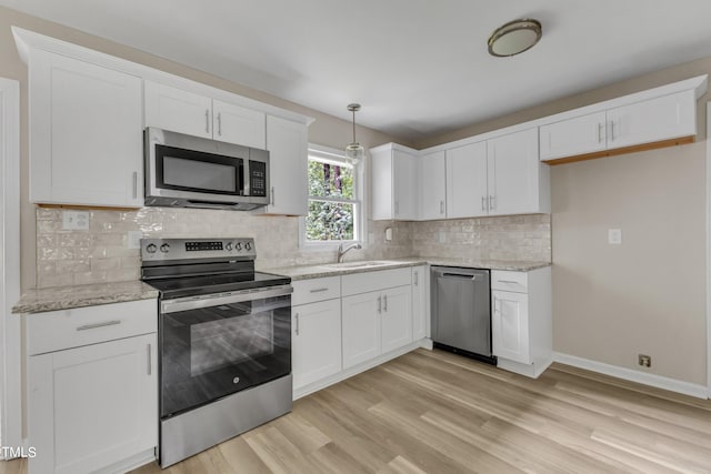 kitchen with stainless steel appliances, light hardwood / wood-style floors, tasteful backsplash, sink, and white cabinets