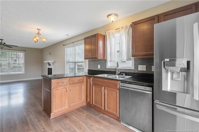 kitchen with appliances with stainless steel finishes, a wealth of natural light, sink, decorative backsplash, and kitchen peninsula