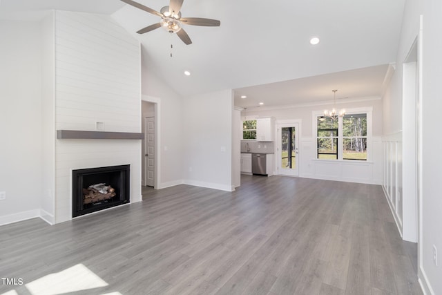 unfurnished living room featuring light hardwood / wood-style flooring, high vaulted ceiling, ornamental molding, a large fireplace, and ceiling fan with notable chandelier