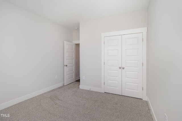 unfurnished bedroom featuring light colored carpet and a closet