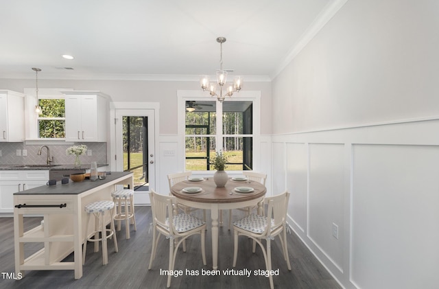 dining room with an inviting chandelier, crown molding, sink, and dark wood-type flooring