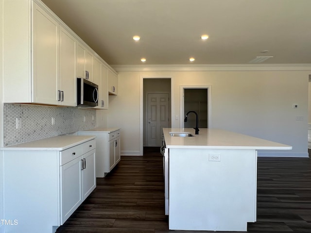 kitchen featuring sink, dark wood-type flooring, white cabinetry, a center island with sink, and decorative backsplash