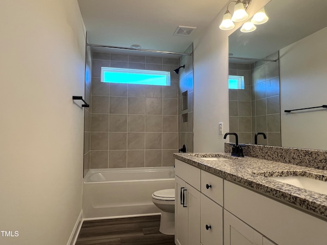 full bathroom featuring tiled shower / bath combo, vanity, hardwood / wood-style floors, and toilet