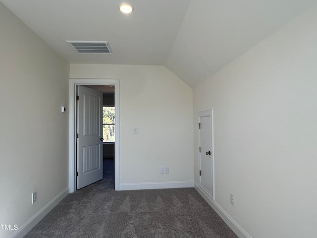 spare room with vaulted ceiling and dark colored carpet