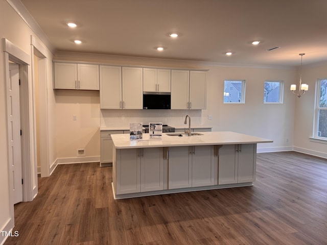 kitchen with dark hardwood / wood-style flooring, sink, decorative light fixtures, and a kitchen island with sink