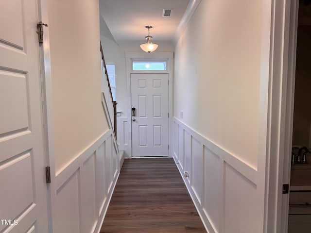 doorway to outside with ornamental molding and dark hardwood / wood-style flooring