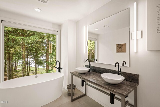 bathroom with tile patterned flooring, a bath, and vanity