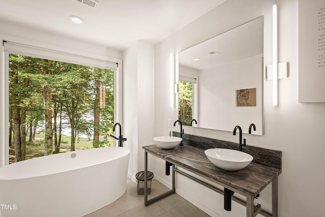 full bath with a wealth of natural light, a sink, and a soaking tub