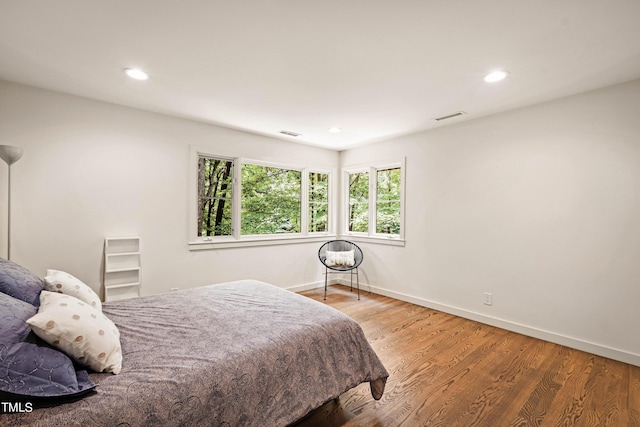 bedroom with wood finished floors, baseboards, and visible vents