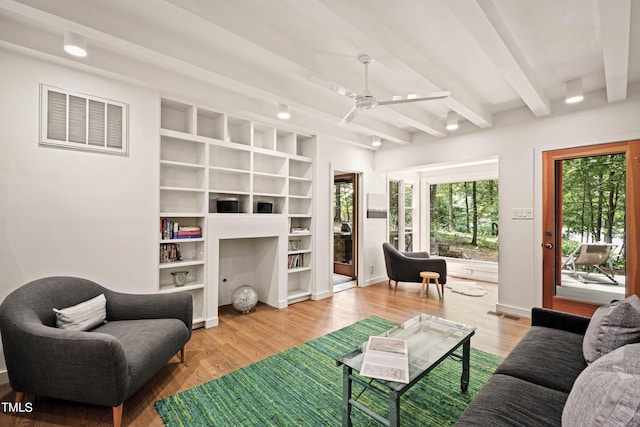 living area with baseboards, beamed ceiling, visible vents, a ceiling fan, and wood finished floors