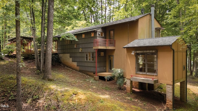 exterior space featuring a balcony and a shingled roof