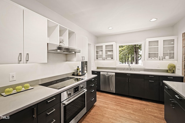 kitchen with white cabinets, sink, light hardwood / wood-style flooring, extractor fan, and stainless steel appliances