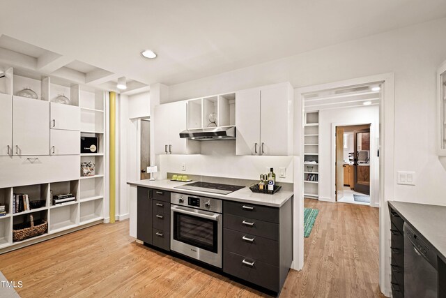 kitchen with white cabinets, beam ceiling, extractor fan, appliances with stainless steel finishes, and light hardwood / wood-style floors