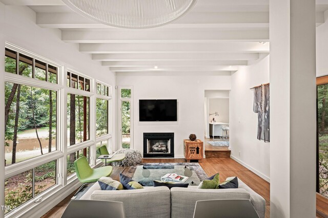 living area featuring baseboards, beamed ceiling, wood finished floors, and a fireplace
