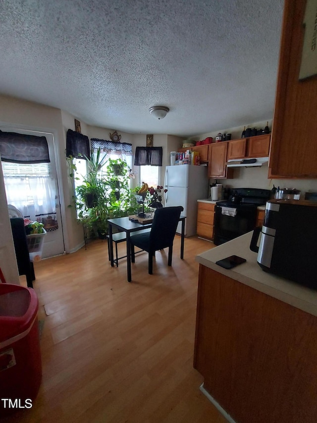 kitchen featuring white refrigerator, a textured ceiling, light wood-type flooring, and black range with electric cooktop