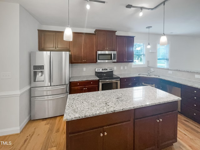 kitchen featuring track lighting, stainless steel appliances, light hardwood / wood-style flooring, and pendant lighting