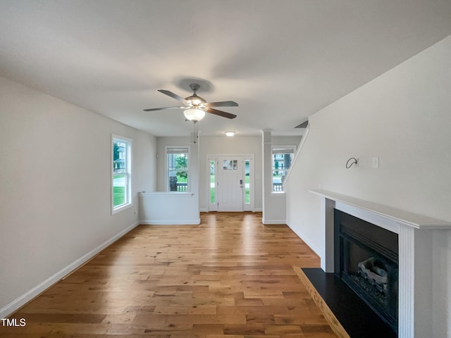 unfurnished living room featuring light hardwood / wood-style floors, decorative columns, and ceiling fan