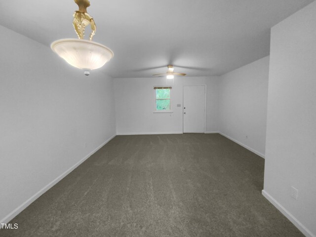 unfurnished room with ceiling fan and dark colored carpet