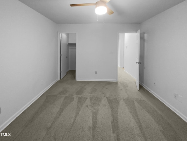 unfurnished bedroom featuring ceiling fan, a walk in closet, a closet, and carpet floors