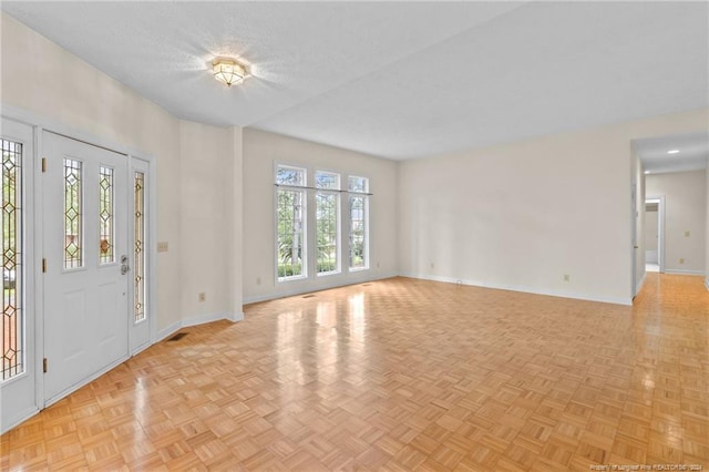 entrance foyer with a textured ceiling, light parquet flooring, and a wealth of natural light