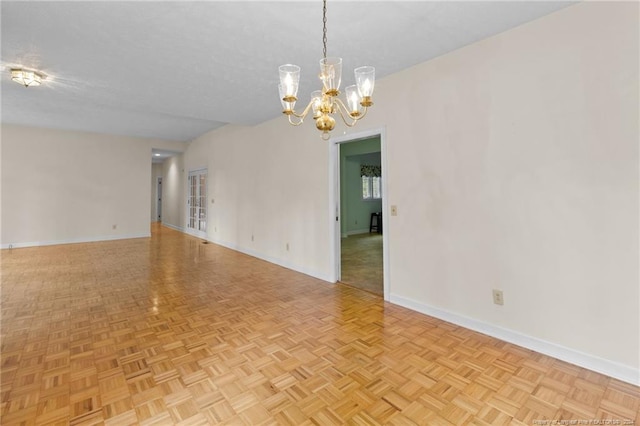 spare room with light parquet flooring, an inviting chandelier, and a textured ceiling