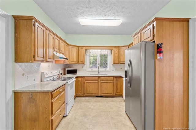 kitchen with white appliances, light stone countertops, sink, and a textured ceiling