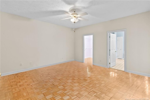 spare room featuring ceiling fan, light parquet floors, and a textured ceiling